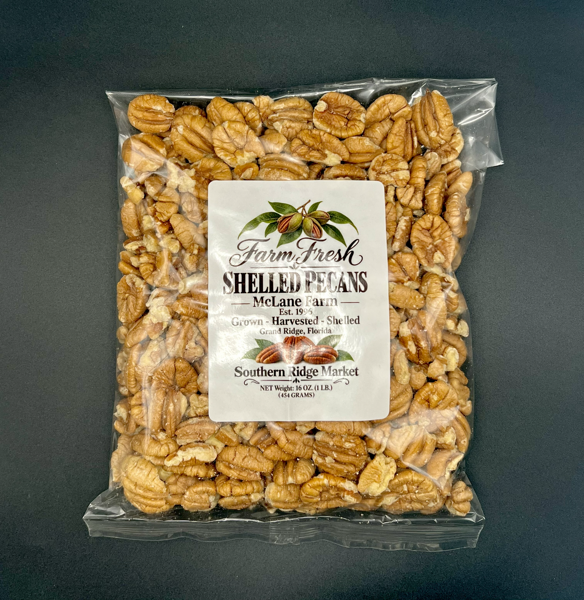 A clear plastic bag filled with shelled pecans and a white label reading 'Farm Fresh Shelled Pecans' on a dark gray background.